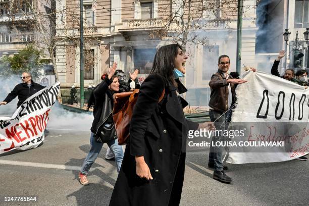 Protesters shout at police firing tear gas while holding a banner reading "Murderers" during a demonstration in Athens on March 5 following a deadly...