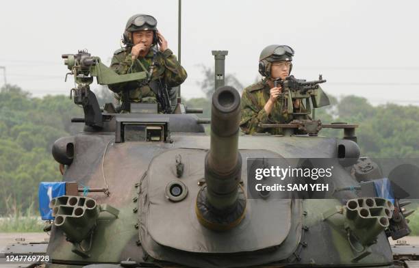 Taiwanese soldiers ride on a CM11 tank during its demonstration before a group of tourists visiting Huko army base in Hsinchu northern Taiwan, 18...