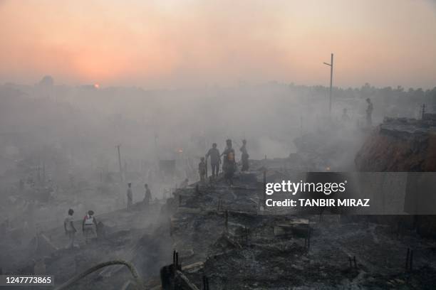 Rohingya refugees search for their belongings after a fire broke out in Balukhali refugee camp in Ukhia on March 5, 2023. - A major fire in a...