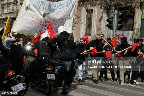 Motorised riot police ride their motorcycles by protesters during a demonstration in Athens, on March 5 following the deadly accident near the city...