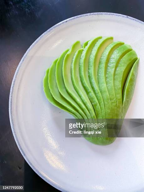 green avocado on a white plate - avocado slices stock pictures, royalty-free photos & images