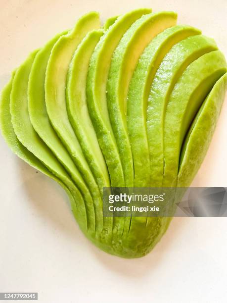 green avocado on a white plate - avocado toast white background stockfoto's en -beelden
