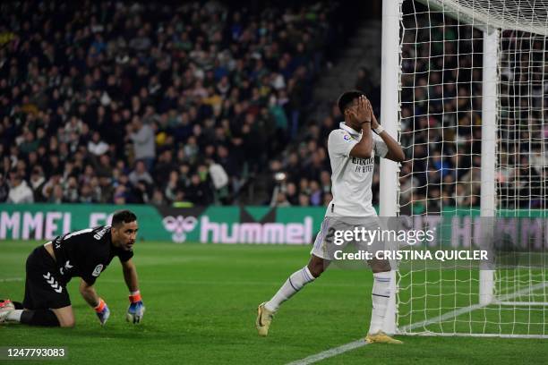 Real Madrid's Brazilian forward Vinicius Junior reacts next to Real Betis' Chilean goalkeeper Claudio Bravo during the Spanish League football match...