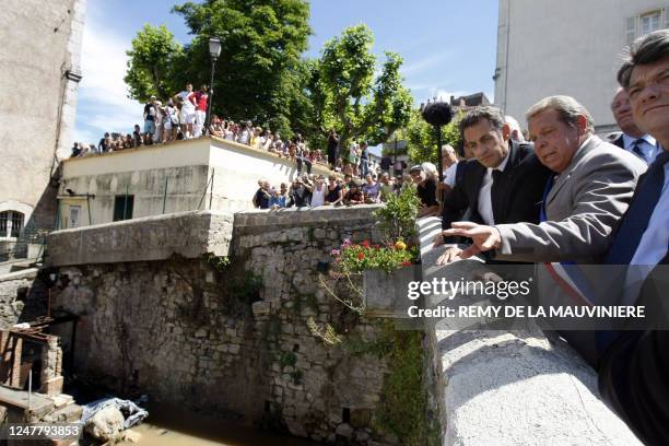 France's President Nicolas Sarkozy listens to explanations from Trans-en-Provence's mayor Jacques Lecointe as he stands on a bridge over the Nartuby...