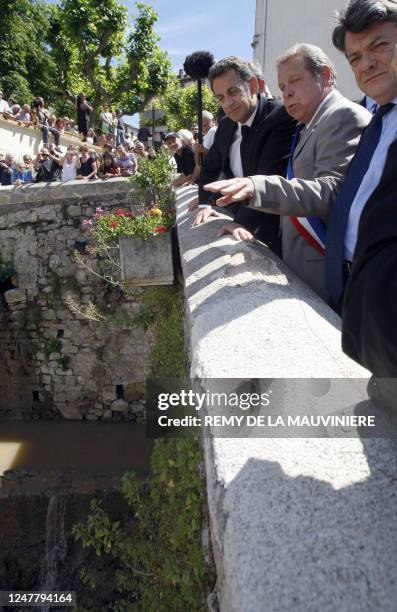 France's President Nicolas Sarkozy listens to explanations from Trans-en-Provence's mayor Jacques Lecointe as he stands on a bridge over the Nartuby...