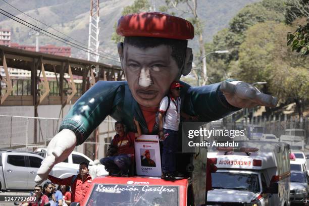 Supporters of late Venezuelan President Hugo Chavez prepare a giant inflatable doll of the former president during commemorations of the 10th...