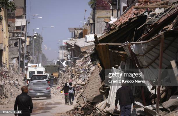 Residents walk on a street past debris of buildings damaged by the Feb. 6 earthquake in Antakya in Turkey's southern Hatay province on March 5, 2023.