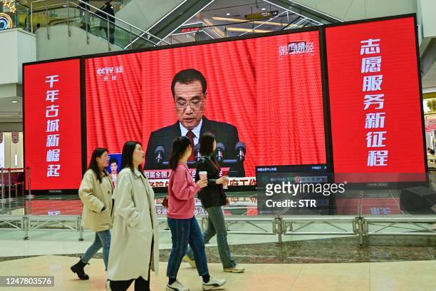This photo taken on March 5, 2023 shows people watching live coverage of the opening session of the National Peoples Congress at a shopping mall in...