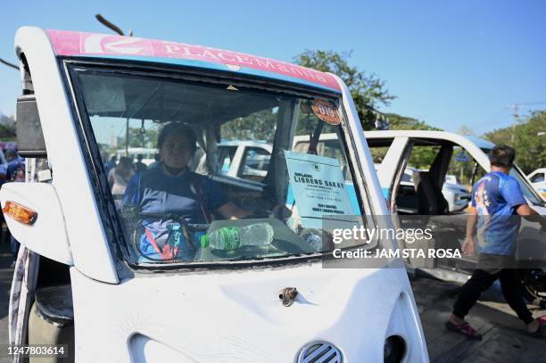 Driver of an electric tricycle waits for passengers as the local governent unit offers free ride in Manila on March 6, 2023. - Operators of...