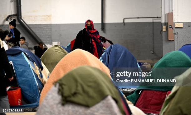 Person looks on as people in administrative difficulties, including undocumented and migrants and asylum seekers, settle in tents installed in a...