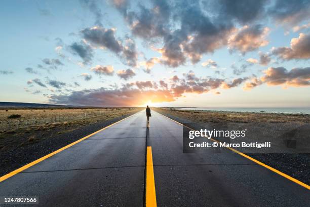 person walking in the middle of the road towards sunset - argentina sunset stock pictures, royalty-free photos & images