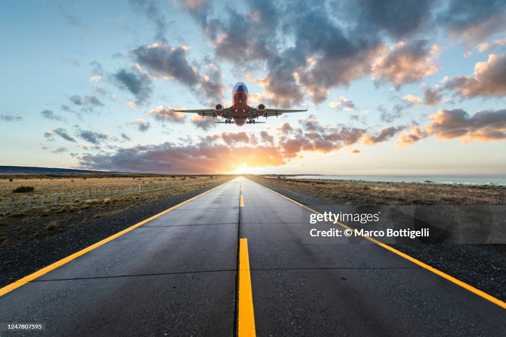 Airplane landing on a road at sunset