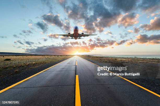 airplane landing on a road at sunset - take off fotografías e imágenes de stock