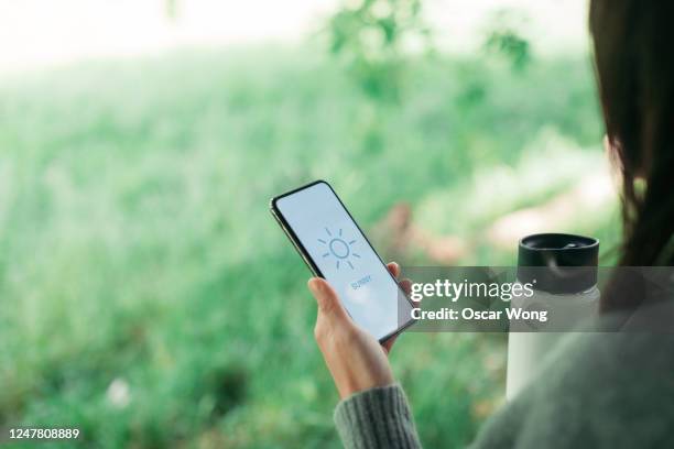 woman checking weather forecast on smartphone display - woman smartphone nature stockfoto's en -beelden