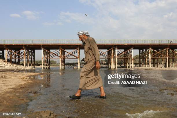 Man crosses the Abu Lehya river, which suffers from drought-induced drop in the water levels, in the Dhi Qar province on March 6, 2023.