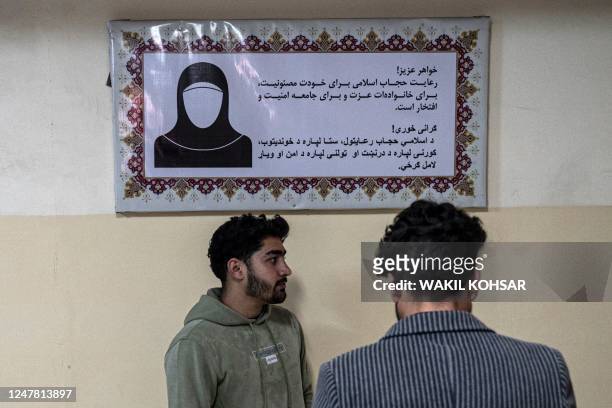 Male students stand in front of a poster ordering women to cover themselves with a Hijab, in the corridor of a private university after the...