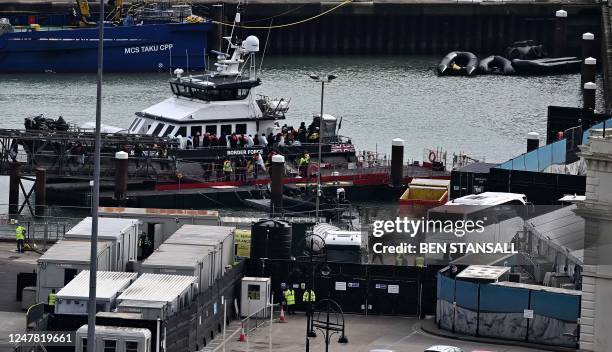 Migrants are escorted ashore from the UK Border Force vessel 'BF Ranger' in Dover, southeast England, on March 6 after having been picked up at sea...