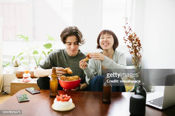 couples mangeant le poulet frit et ayant une bière - woman eating chicken photos et images de collection