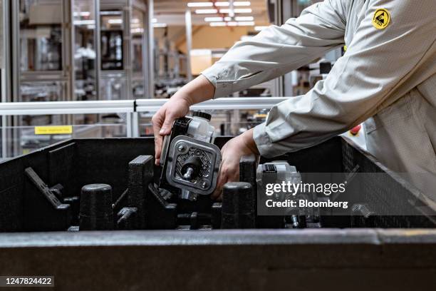 An employee places a part of an MK C2 brake system module in a container on the production line at the Continental AG manufacturing plant in...