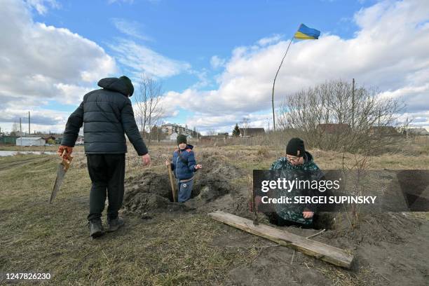 Boys dig trenches as they play outside the town of Borodyanka, Kyiv region, to prevent the Russian army re-occupation of the town on March 6, 2023.