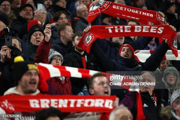 Brentford fans hold up their scarves as they sing ahead of kick-off during the English Premier League football match between Brentford and Fulham at...