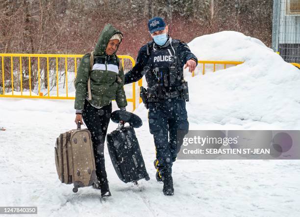 An officer walks with a migrant as they arrive at the Roxham Road border crossing in Roxham, Quebec, Canada, on March 2, 2023. - In 2022, the number...