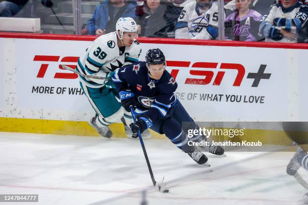 Vladislav Namestnikov of the Winnipeg Jets plays the puck up the ice as Logan Couture of the San Jose Sharks gives chase during first period action...