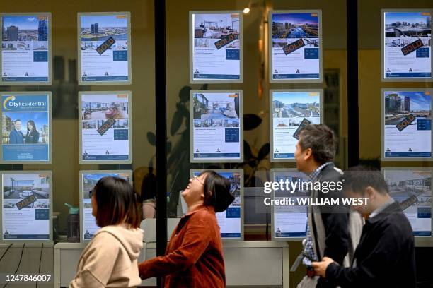 People walk past a real estate agent's window in Melbourne on March 7 as the Reserve Bank of Australia raises interest rates for the 10th consecutive...