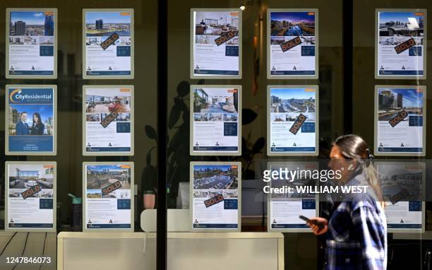 People walk past a real estate agent's window in Melbourne on March 7 as the Reserve Bank of Australia raises interest rates for the 10th consecutive...