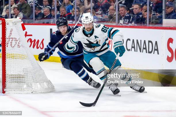 Erik Karlsson of the San Jose Sharks plays the puck around the net as Nikolaj Ehlers of the Winnipeg Jets gives chase during first period action at...