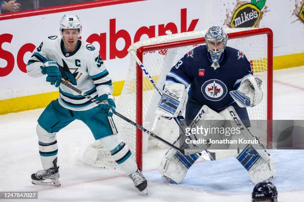 Logan Couture of the San Jose Sharks and goaltender David Rittich of the Winnipeg Jets keep an eye on the play during second period action at the...