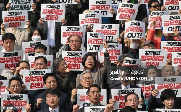 South Korean lawmakers and protesters hold placards during an anti-government rally denouncing South Korea's plans to compensate victims of Japan's...