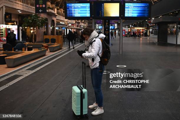 Traveller stands near information screens at the Gare de l'Est railway station in Paris, on March 7 as fresh strikes and protests are planned against...