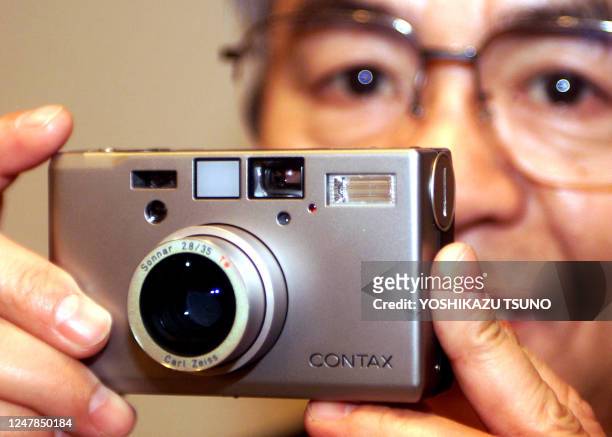 Kensuke Itoh, Chairman of Japan's Kyocera displays the company's high-grade compact camera "Contax T3" at a press meeting in Tokyo 21 February 2001...