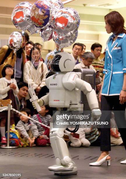 Humanoid robot Asimo, produced by Japan's auto giant Honda, carries balloons to give to children at the company's showroom in Tokyo 01 April 2001....