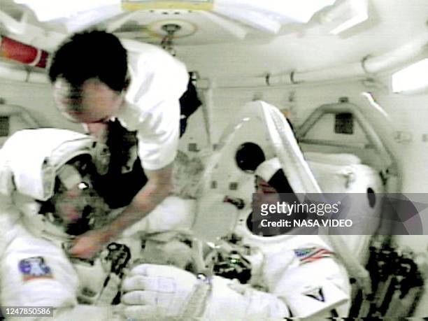 Space shuttle Atlantis Pilot Mark Polansky helps Tom Jones with his helmet, 12 February 2001, as Robert Curbeam watches in the shuttle's airlock in...