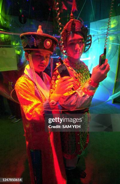 Two Taiwanese models wear ancient traditional Chinese dresses and dial their mobile phones inside the "bubble, a transparent plastic zone to avoid...