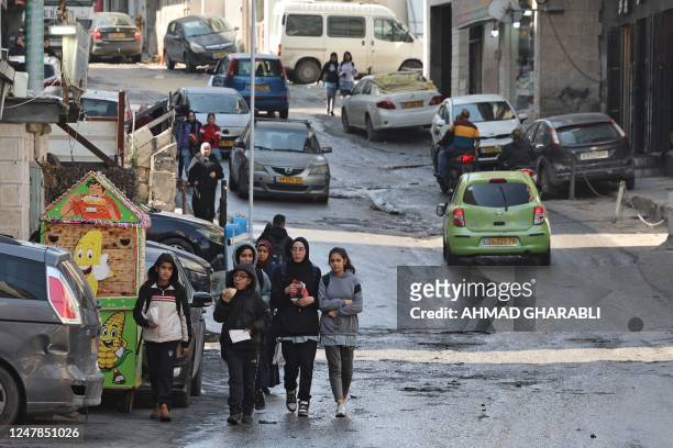 Palestinian students walk down a street in east Jerusalem's Shuafat refugee camp on February 22, 2023.