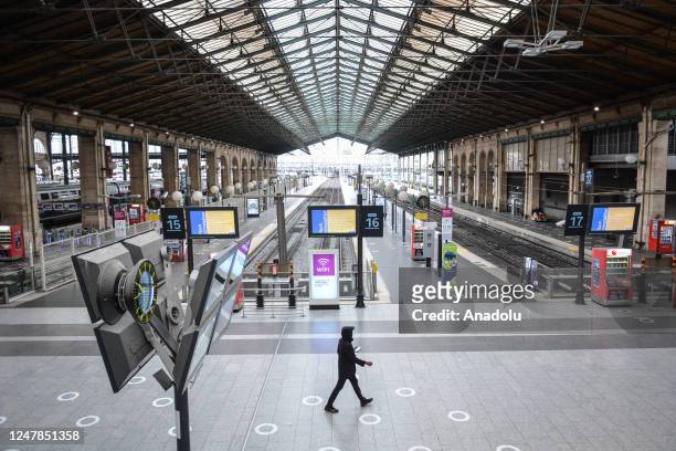 Passenger walks past empty railways at the Gare du Nord train station in Paris on March 7 as employees hold a strike against French President's plan...