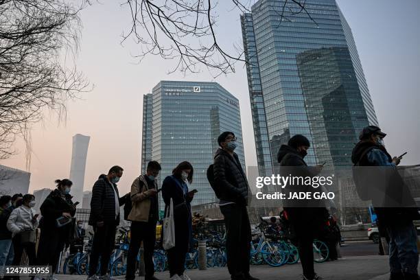 People wait for a bus in the central business district during rush hour in Beijing on March 7, 2023.