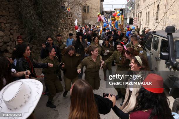 Israeli soldiers and people dance as Israeli settlers celebrate the carnival-like Purim holiday at al-Shuhada street, largely closed to Palestinians,...