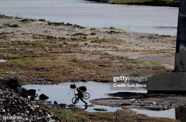 Bicyclist crosses a puddle along the banks of the Los Angeles River, which had a lot of debris and trash near its mouth in Long Beach on Monday, Mar....