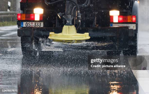 March 2023, Lower Saxony, Bramsche: A vehicle from the winter road maintenance service is in operation on a road, spreading road salt on the roadway....