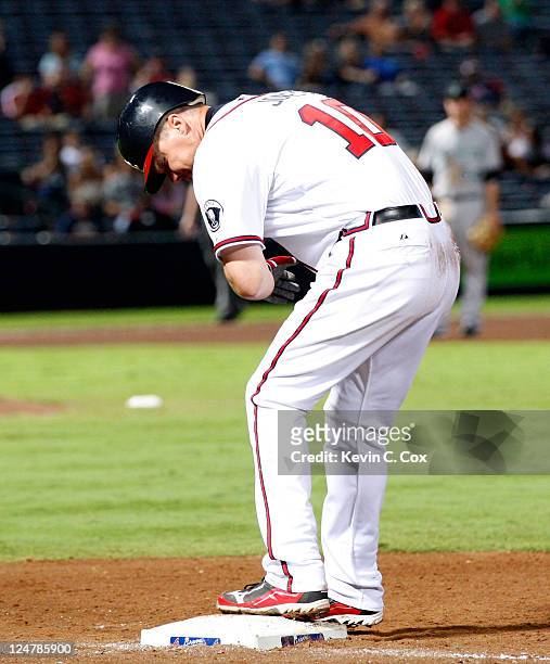 Chipper Jones of the Atlanta Braves stands on first base after beating out a ground ball in a collision at first base against the Gaby Sanchez of the...