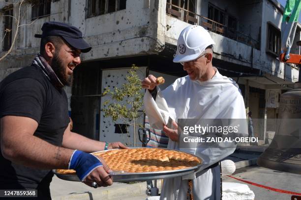 Man offers sweets during the installation on February 28, 2023 of three bronze bells cast in Normandy in the bell tower of the historic Roman...