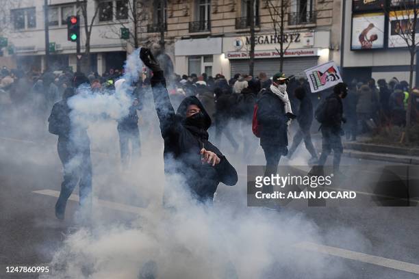 Protester throws a smoking projectile during clashes with police on the sidelines of a demonstration in Paris on March 7 during a nationwide day of...