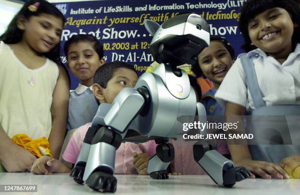 Bangladeshi children are amused by the robot-dog "Aibo" presenting its skills during a show in Dhaka, 10 June 2003. In the first ever such show,...