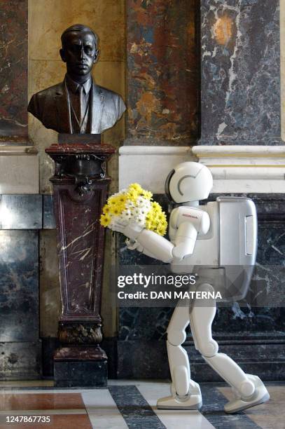 Talking robot Asimo, a 1.2-meter tall robot made by Honda, lays a bunch of flowers 22 August 2003 at the bust of Czech writer Karel Capek at the...