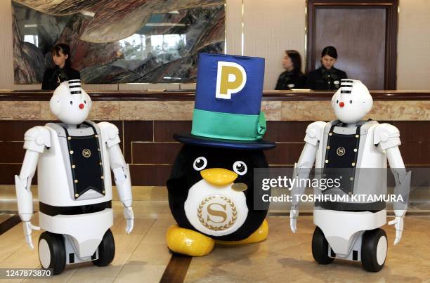 The mascot for the Sheraton hotel group, Penton , poses with Hitachi's humanoid robots "EMIEW" in front of the front desk of the Sheraton Grande...