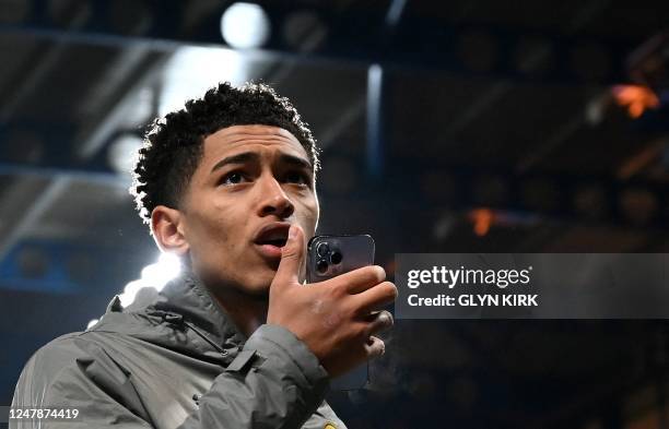 Dortmund's English midfielder Jude Bellingham speaks in his phone as he walks on th pitch after the UEFA Champions League round of 16 second-leg...